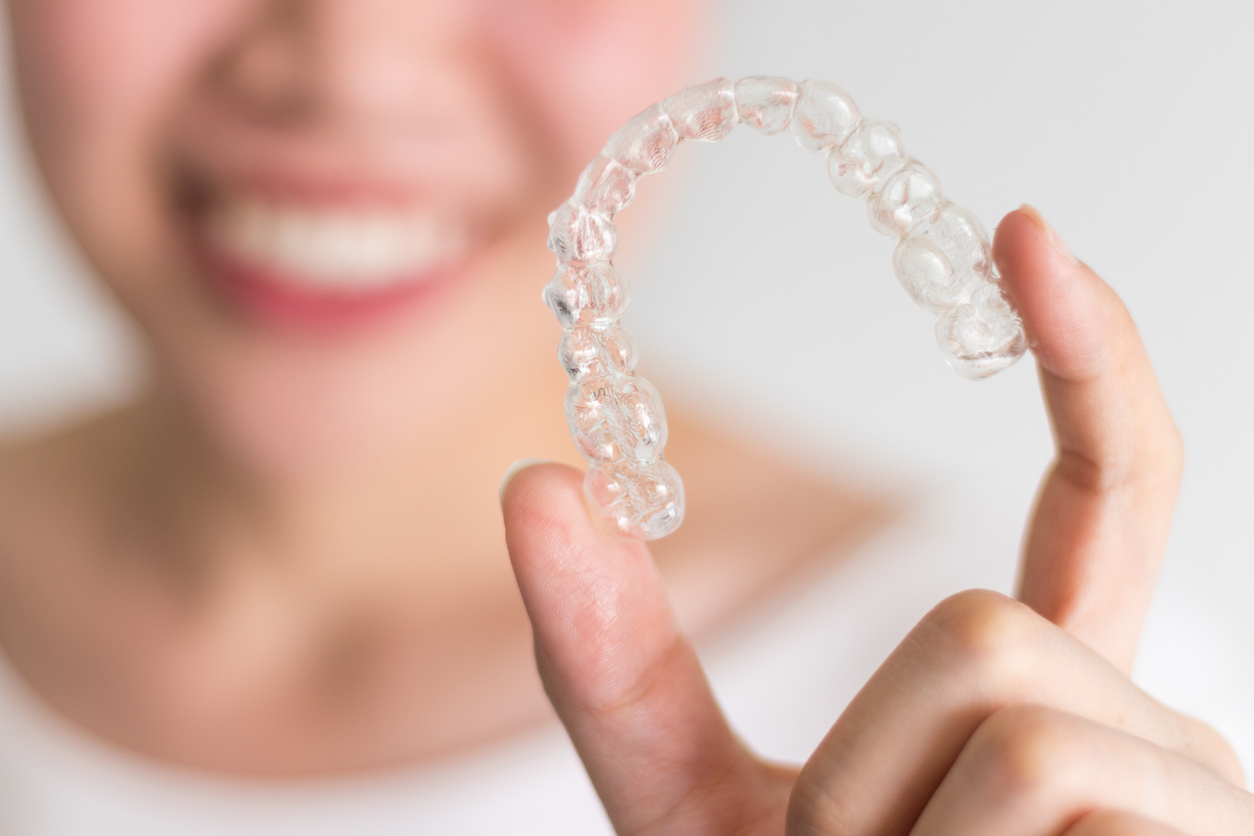 Woman holding up her clear aligners.